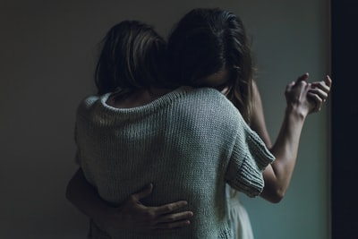 Two women embrace together
